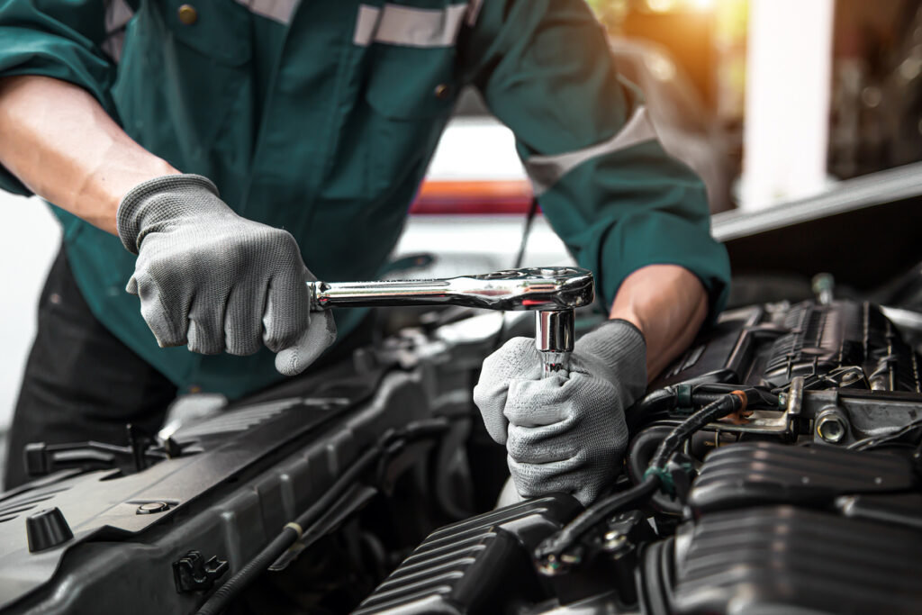 A mechanic in a green shirt performing a Log book service on a car engine