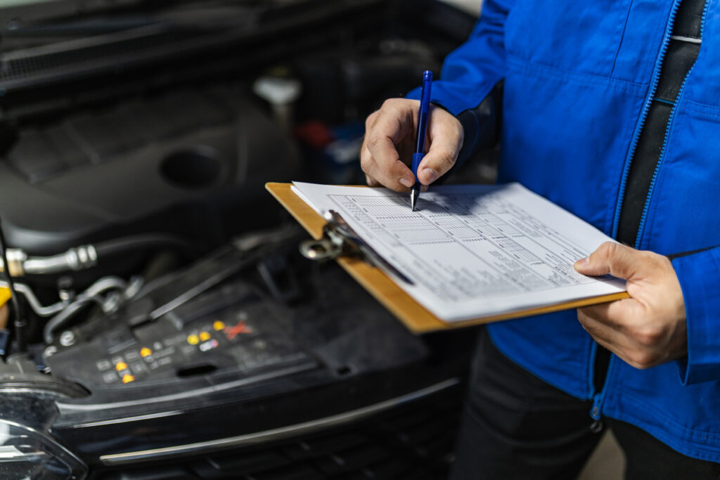 A mechanic in a blue jacket filling out a checklist during a log book car service geelong 