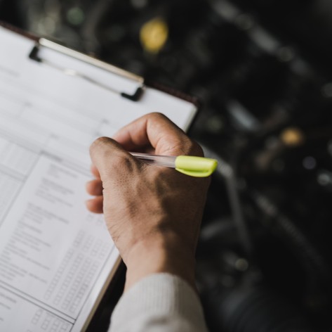 A close up of a hand holding a pen ticking off a checklist during a roadworthy inspection