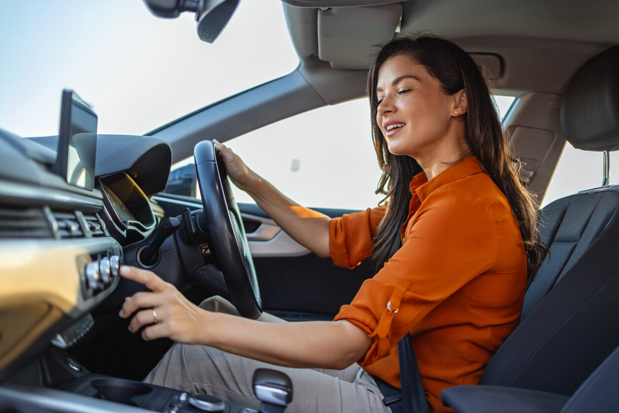 Smiling woman sitting in the driver's seat buy hybrid car.