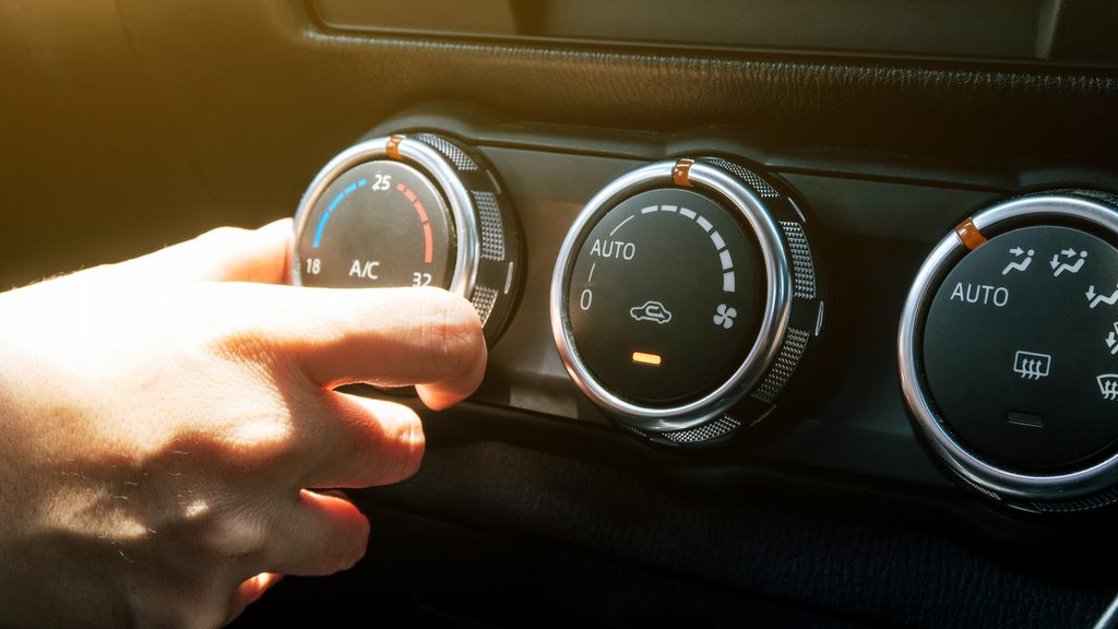 A hand reaching out to adjust the car air conditioning geelong
