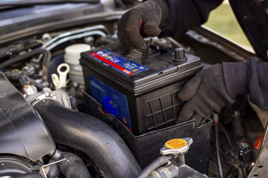 A gloved mechanic doing a car battery replacement geelong