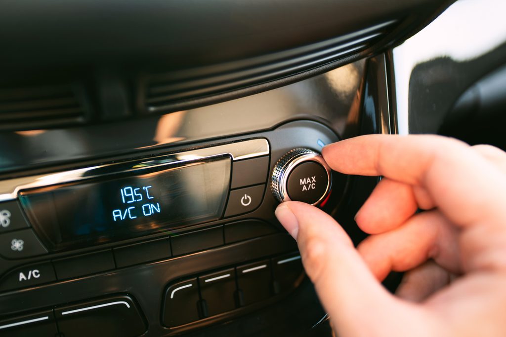 Hand adjusting the car air conditioning service dial in a modern car.