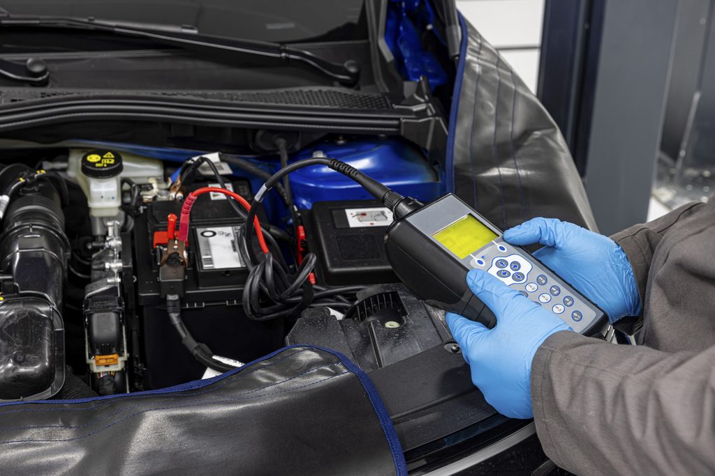 Mechanic wearing blue gloves doing a car battery service